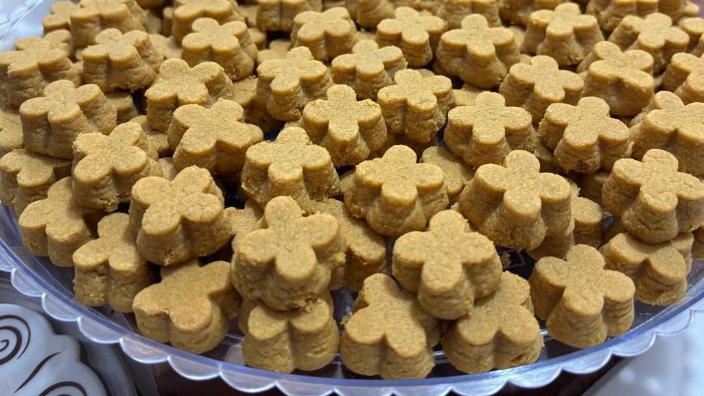 Imagen en primer plano de un plato lleno de galletas pequeñas, cada una con una forma distintiva similar a un trébol de cuatro hojas.