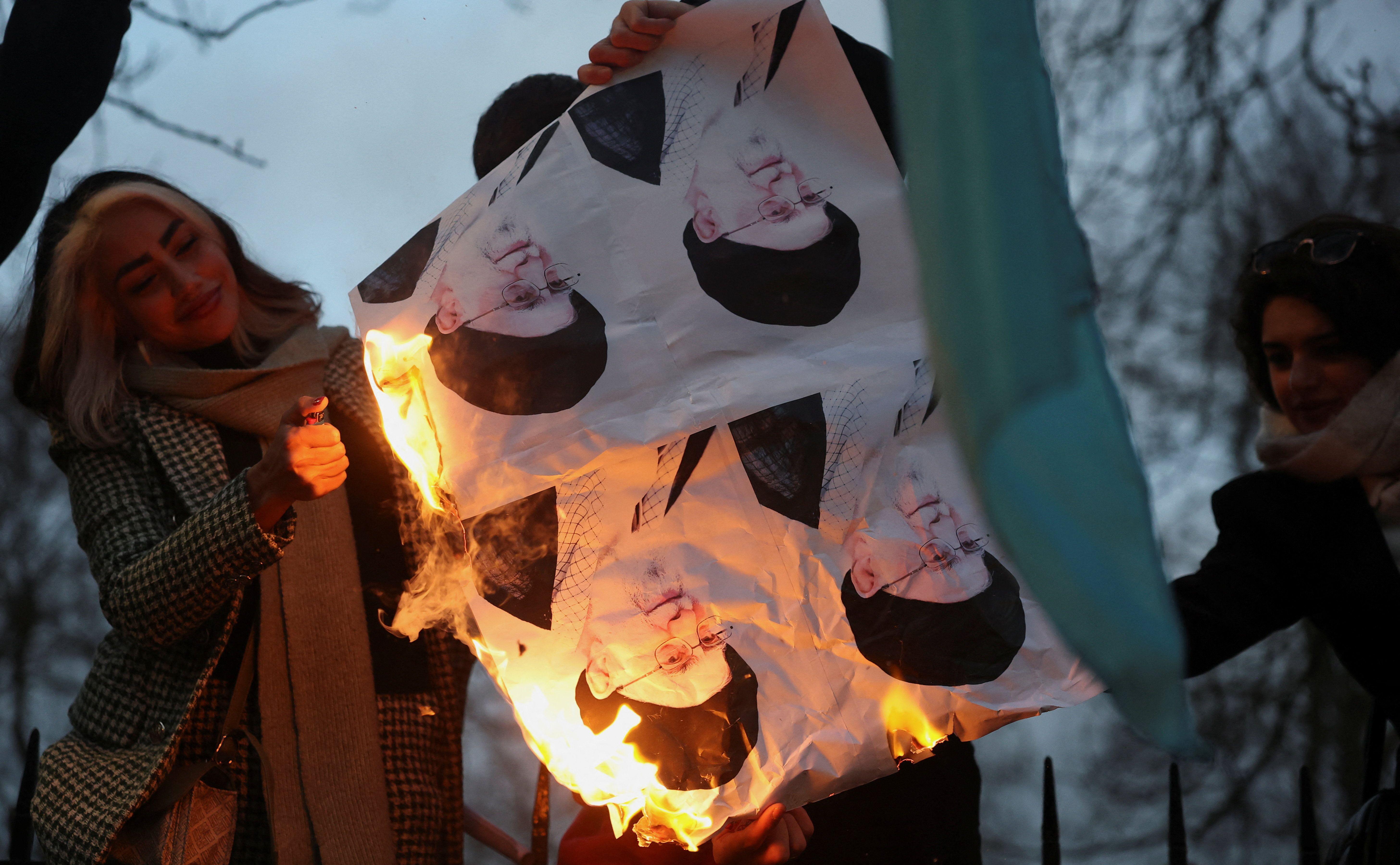 Jovem sorri ao ver fotos de Khamenei queimando