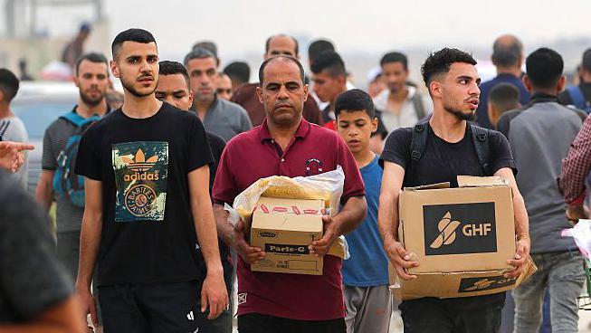 Un palestino carga una caja con ayuda humanitaria