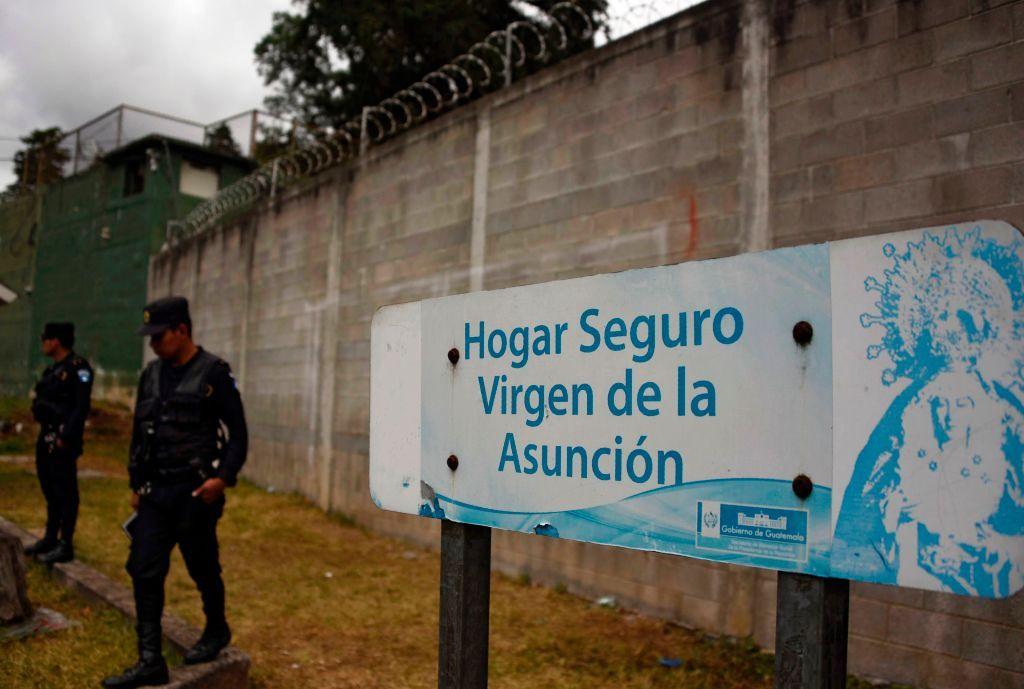 Agentes de policía hacen guardia junto a un cartel que dice "Hogar Sage Virgen de la Asunción" en la entrada del refugio infantil después de que 40 niñas murieran en un incendio el 8 de marzo, en San José Pinula, a unos 10 kilómetros al este de la ciudad de Guatemala, el 15 de marzo de 2017. (Foto: JOHAN ORDONEZ/AFP a través de Getty Images)
