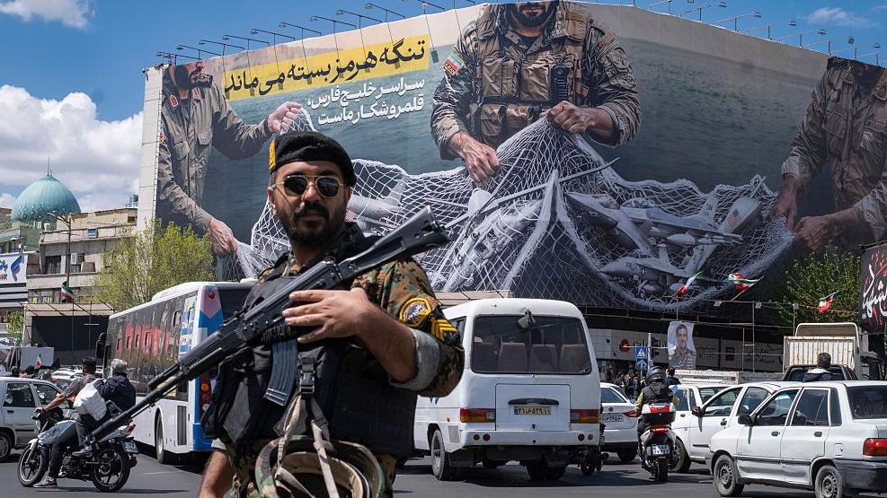 Un soldado iraní y detrás una pancarta sobre el estrecho de Ormuz