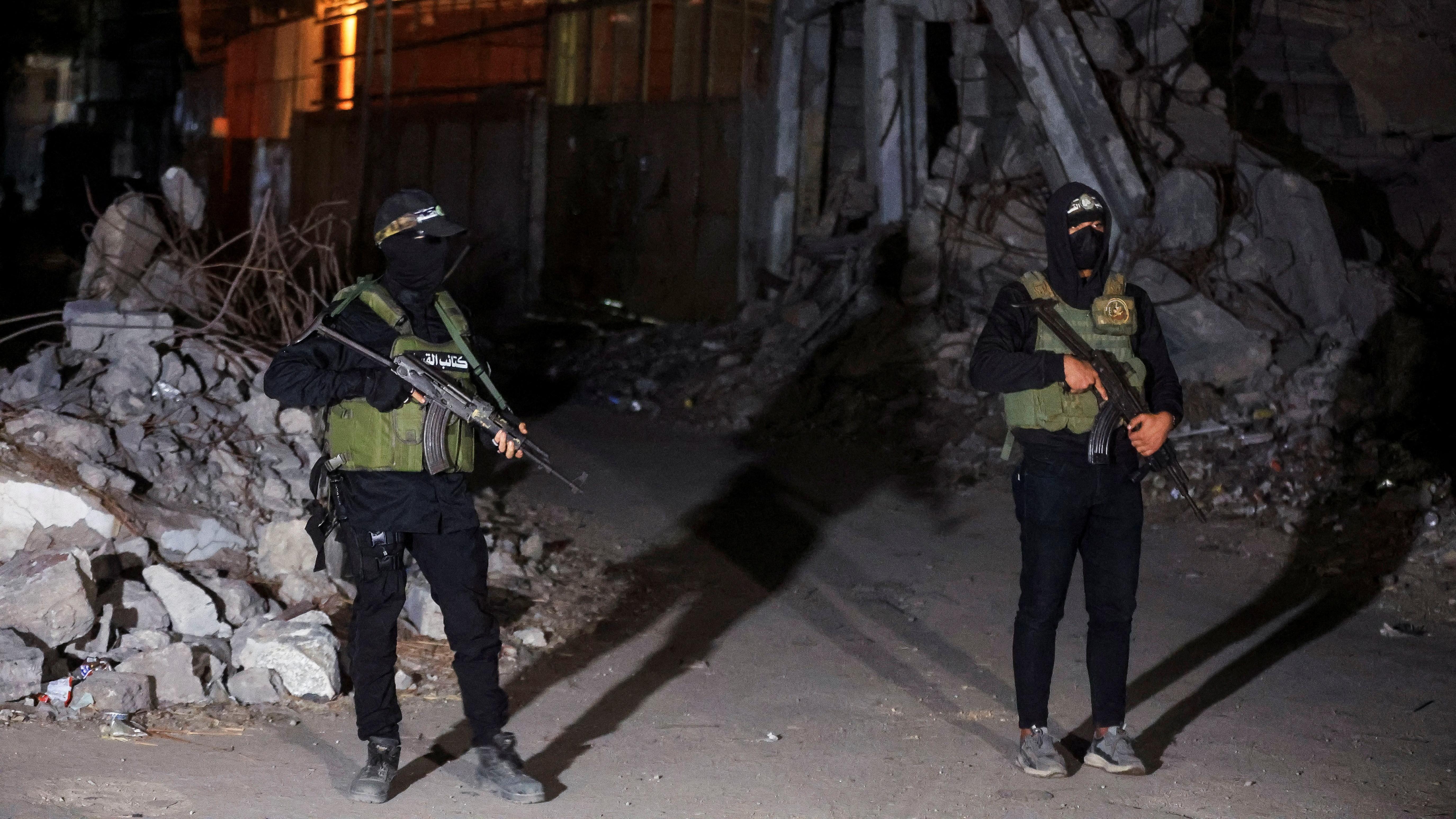 يقف مسلحون من حماس حراساً بينما يتم تسليم جثث الرهائن الذين احتُجزوا في غزة