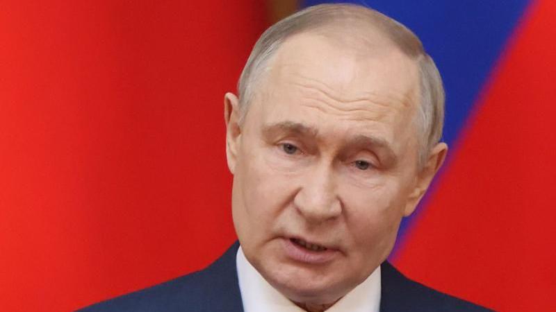 Presidente russo Vladimir Putin, frente a um fundo vermelho e azul