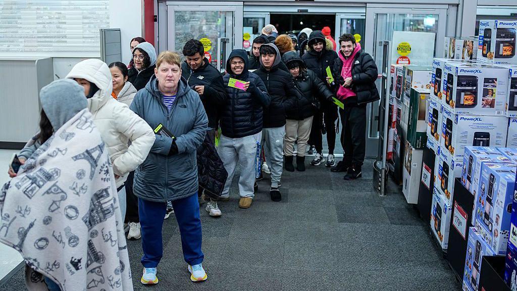 Varias personas que han pasado la noche haciendo cola a las puertas de un Target en Estados Unidos acceden a la tienda cuando abre.