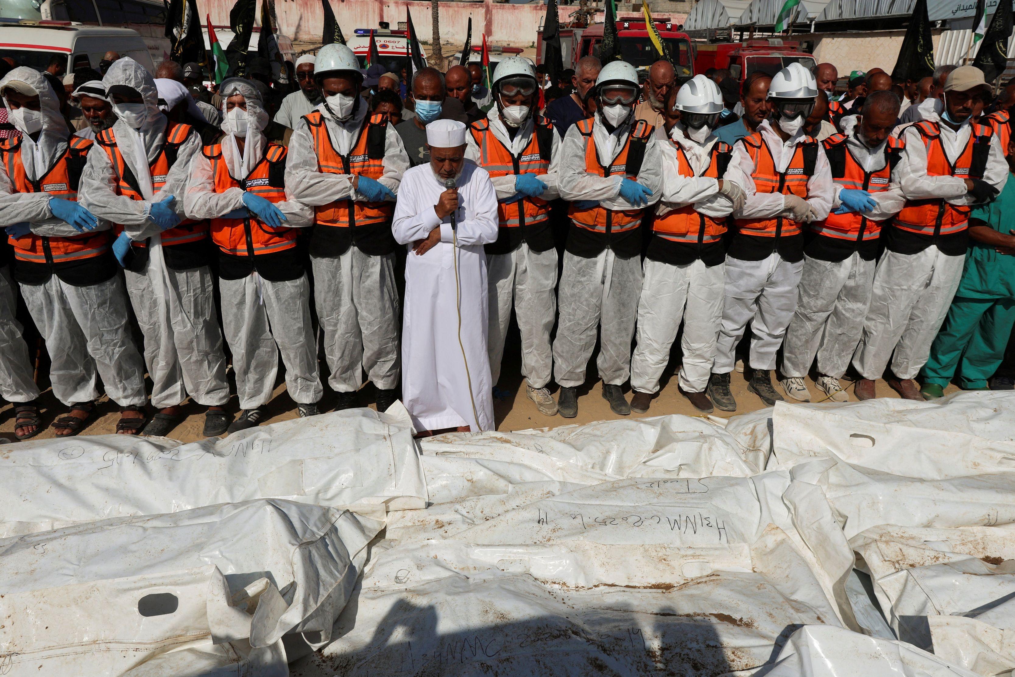 جثث مشوهة و"آثار تعذيب"، كيف يتعرف فلسطينيون على ذويهم في قطاع غزة؟ 3 فلسطينيون يؤدون صلاة الجنازة على جثامين مجهولة الهوية قبل دفنها في مقبرة جماعية في دير البلح