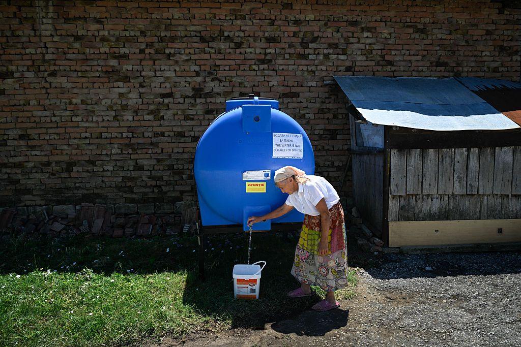 starija žena punu kofu vode sa cisterne u Bugarskoj 