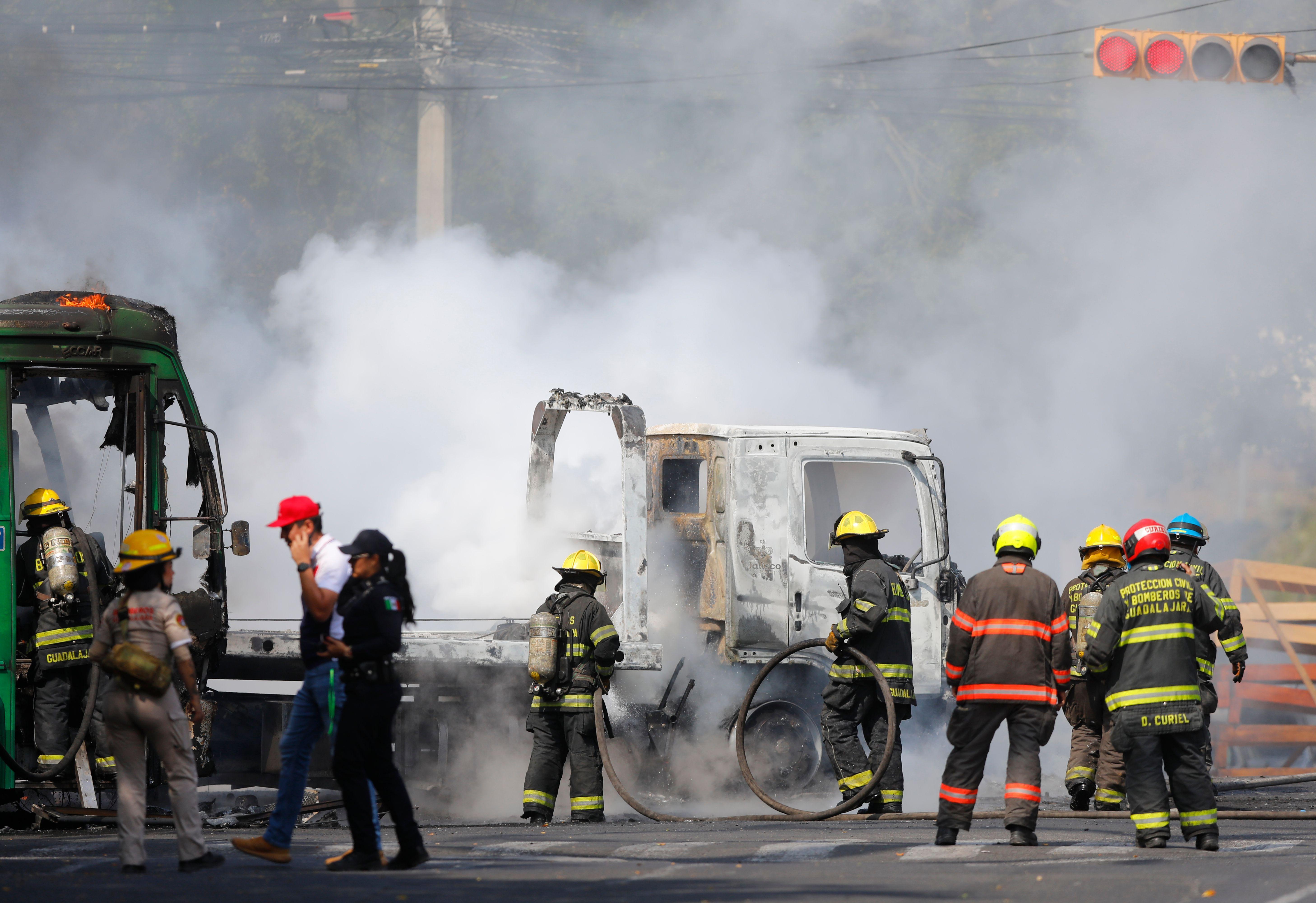 Membros do Corpo de Bombeiros de Guadalajara trabalham para extinguir um inc&ecirc;ndio que envolve v&aacute;rios ve&iacute;culos em Guadalajara, no M&eacute;xico, em 22 de fevereiro de 2026. Um caminh&atilde;o e um &ocirc;nibus est&atilde;o em chamas, cercados por um grande grupo de bombeiros.