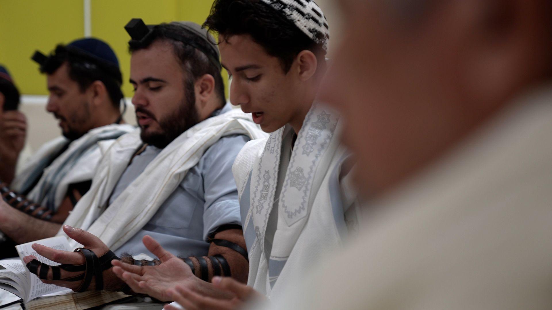Homens alinhados rezam com trajes judaicos