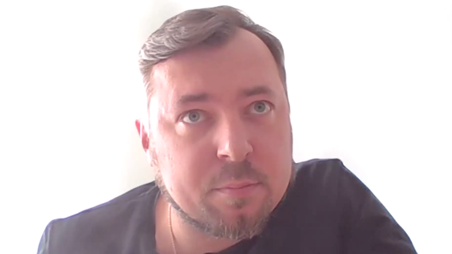 m homem de olhos azuis, cabelos grisalhos, veste uma camiseta escura