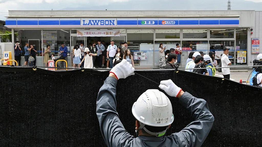 많은 사람이 몰린 일본 로손 편의점 앞에 가림막을 설치하는 인부의 뒷모습