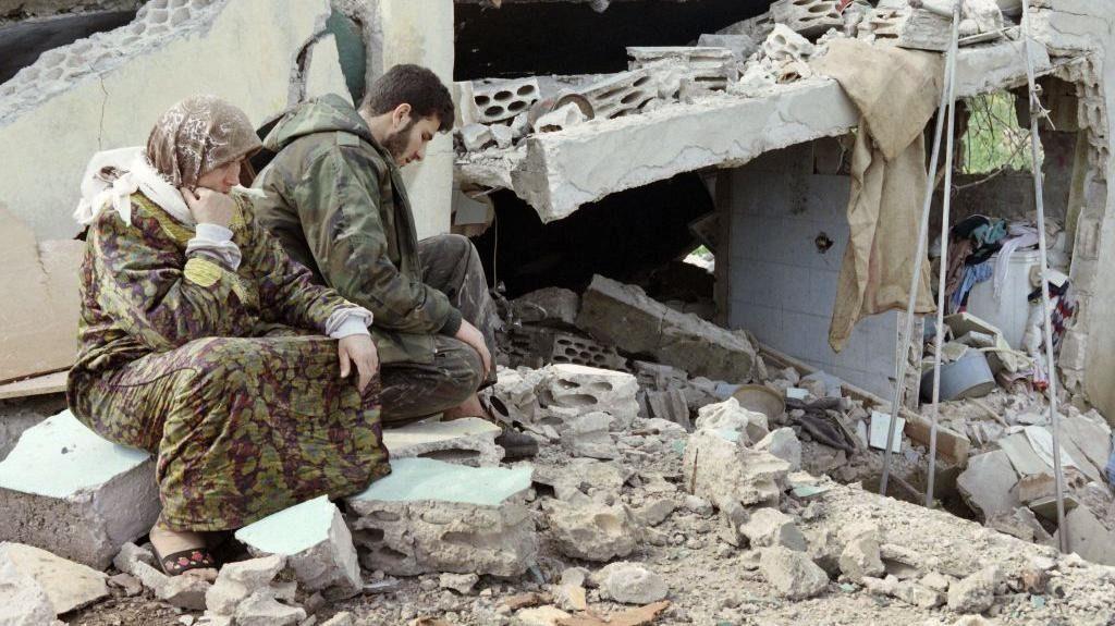 مقاتل لبناني من حزب الله يجلس مع والدته بجوار منزلهم المدمر في جنوب لبنان، في 28 أبريل/نيسان 1996
