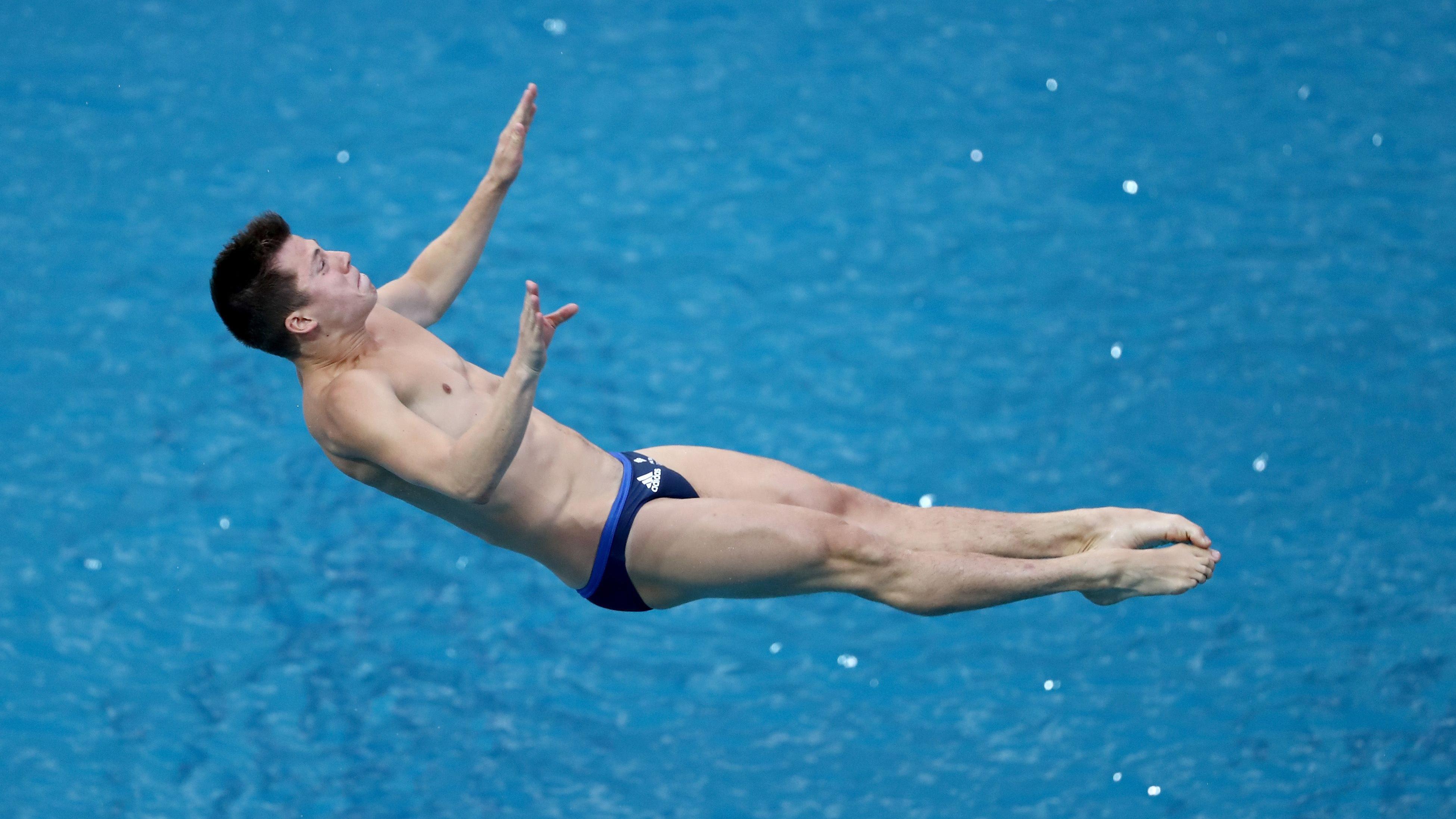 Un joven con un bañador azul del equipo de Gran Bretaña aparece en la foto en pleno salto. 