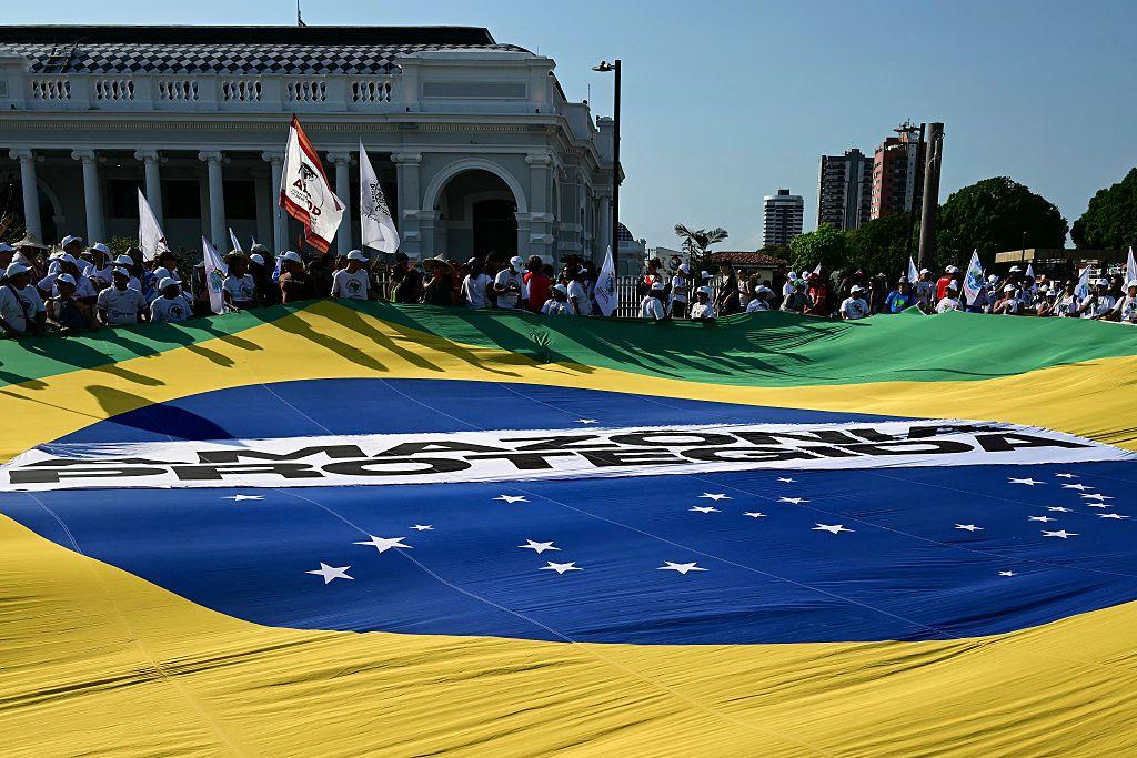 Manifestantes exibem uma enorme bandeira brasileira com os dizeres 'Amazônia Protegida' (em vez de Ordem e Progresso) durante a chamada 'Grande Marcha do Povo' à margem da Conferência das Nações Unidas sobre Mudanças Climáticas COP30, em Belém (PA)