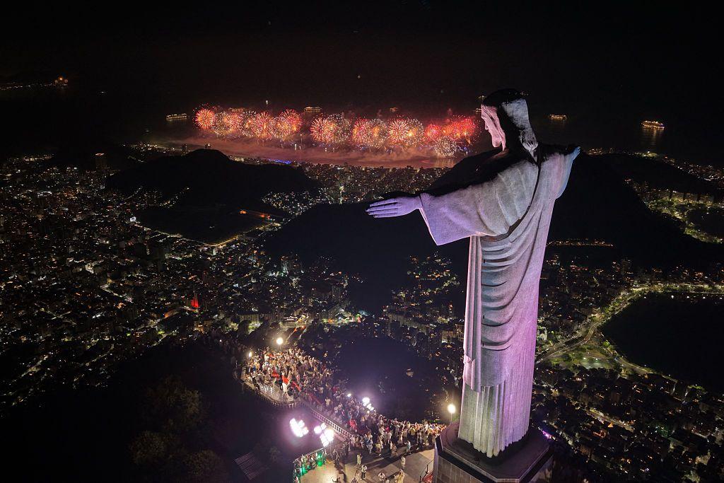 Una vista aérea de la estatua de Cristo Redentor y la panorámica de la playa de Copacabana iluminada con fuegos artificiales