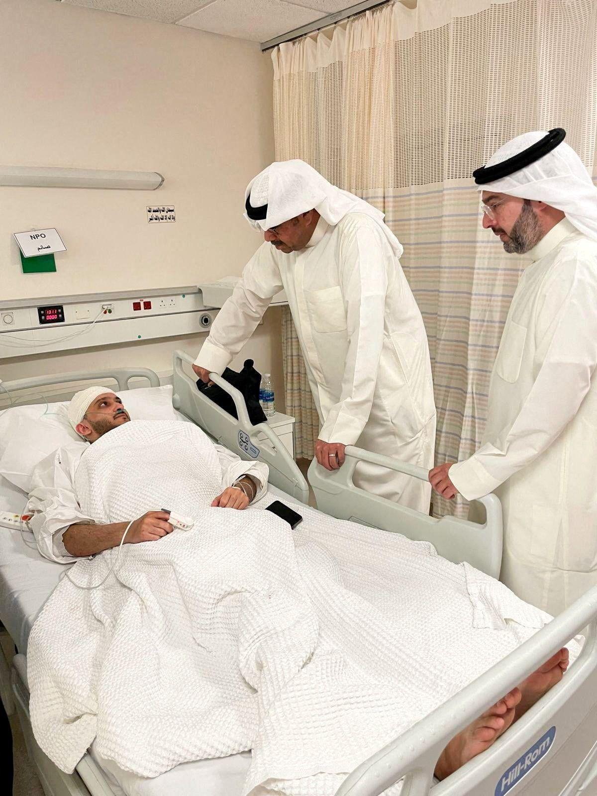 El ministro de Defensa kuwaití, el jeque Abdullah Ali Abdullah al Salem al Sabah, un hombre con túnica blanca mira a una persona en una cama, con la cabeza con vendas.