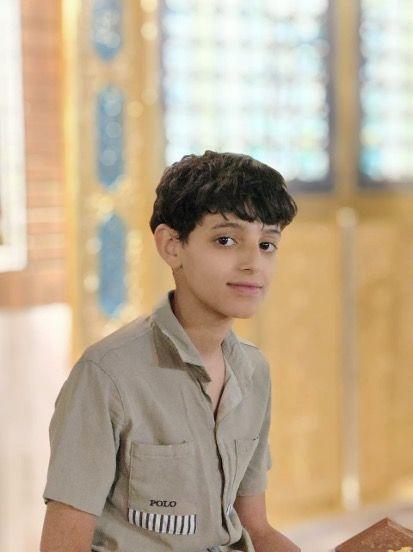 الطفل مهدي من العراق يرتدي قميصاً بنياً