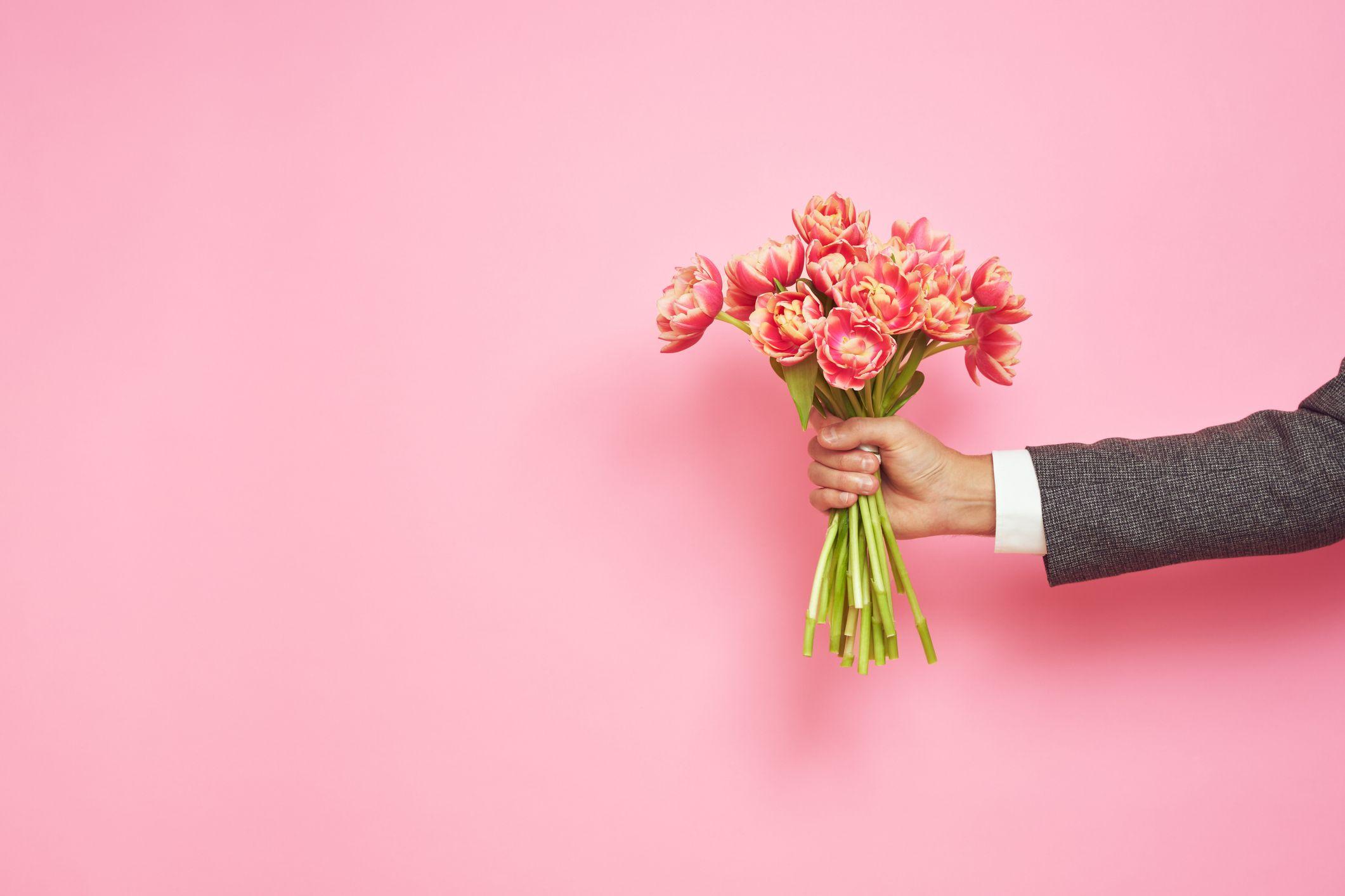 Mão de homem segurando buquê de flores