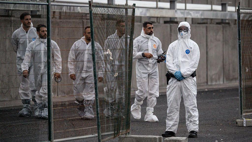Trabajadores llegan con ropa de protección tras el atraque del MV Hondius en el puerto de Granadilla el 10 de mayo de 2026 en Tenerife
