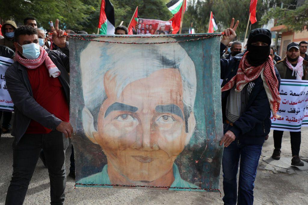 مجموعة من الناشطين الفلسطينيين يحملون يافطات وأعلام فلسطينية وأعلام الجبهة الشعبية لتحرير فلسطين، في مظاهرة يتقدمهم، اثنان يغطيان وجههما ويحملان صورة لسعدات.