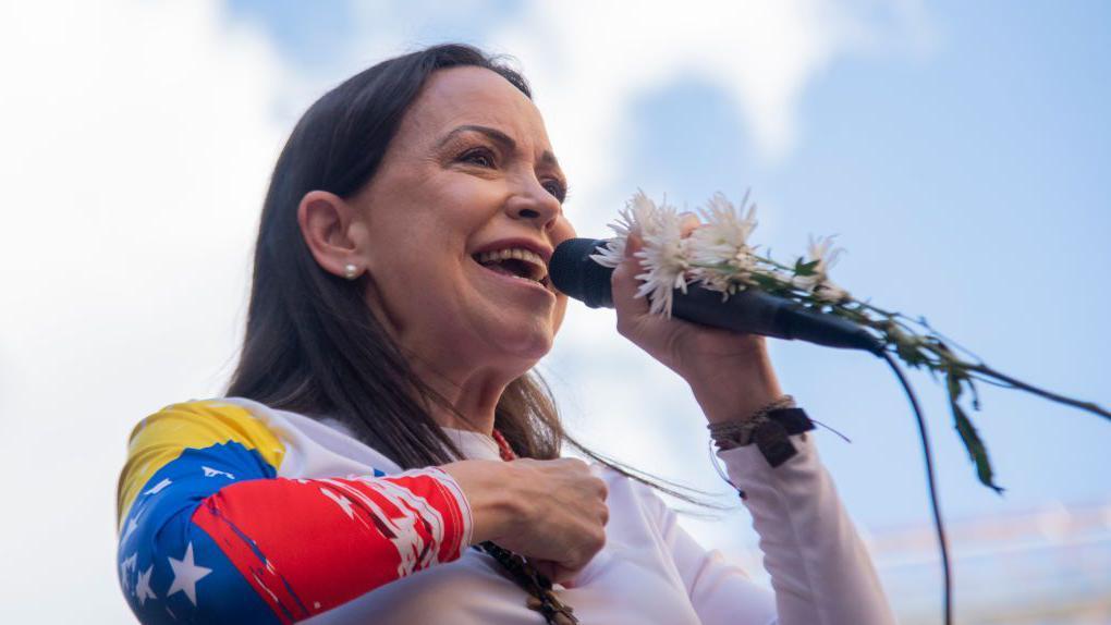 María Corina Machado sosteniendo un micrófono