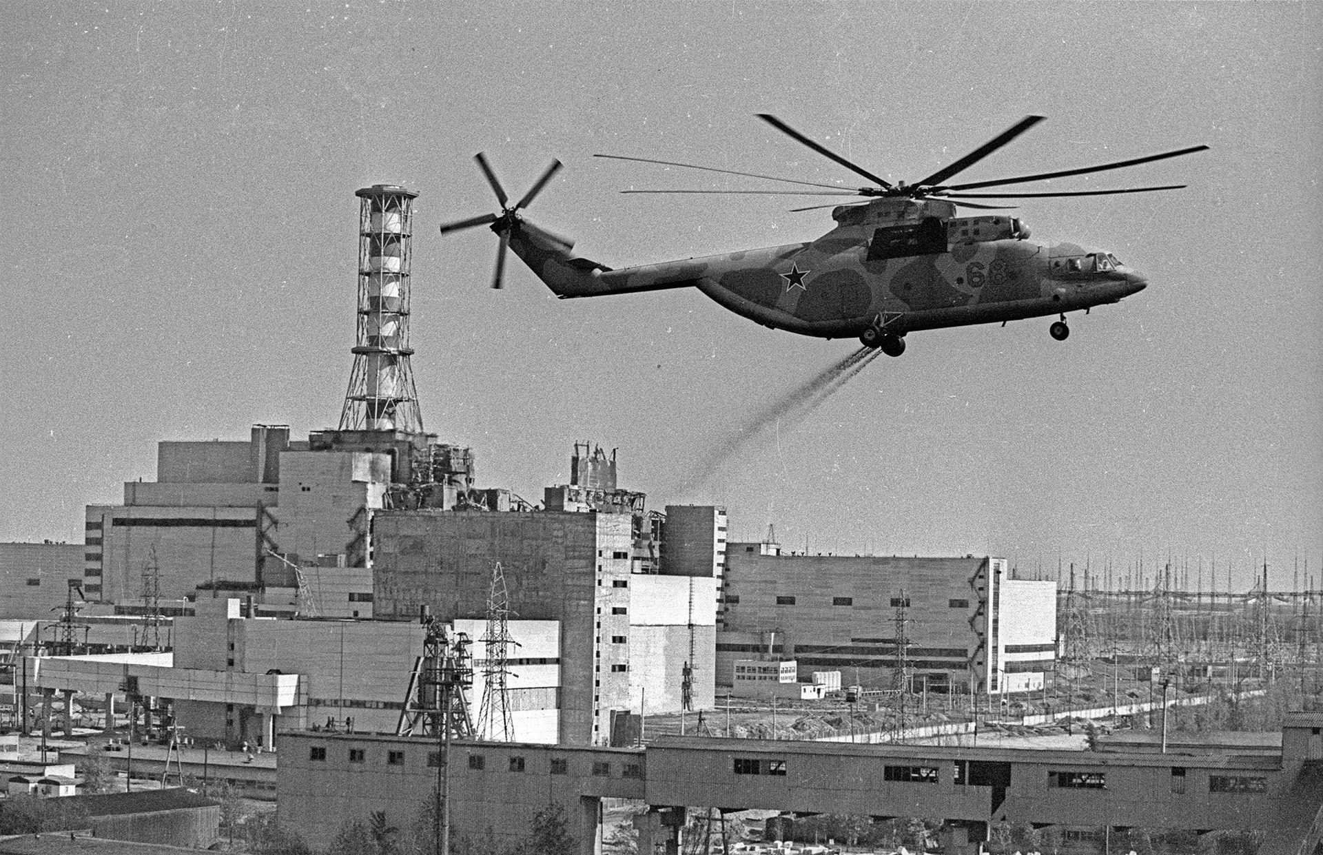 Uma foto de arquivo em preto e branco mostra um helic&oacute;ptero espalhando componentes de descontamina&ccedil;&atilde;o sobre a &aacute;rea contaminada da Usina Nuclear de Chernobyl