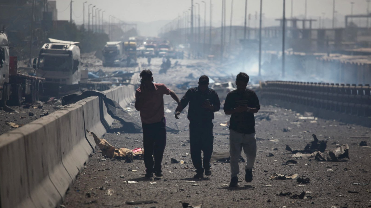 Three men rush down a highway littered with detritus and rubble after the massive port explosion