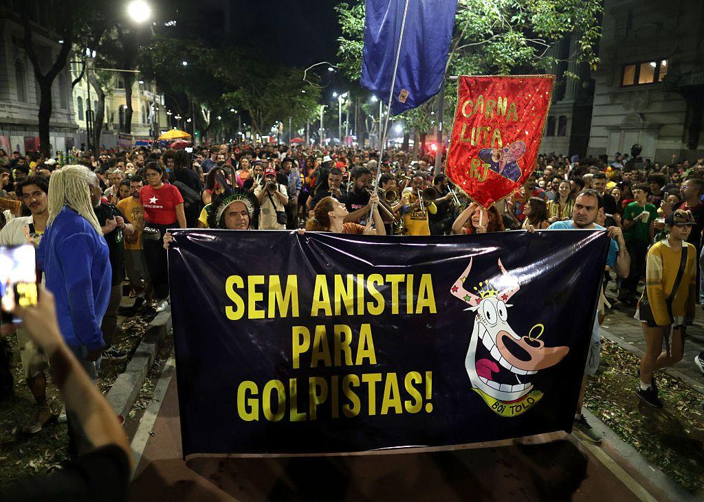Manifestantes à noite, com estandartes de carnaval e cartaz que diz 'Sem anistia para golpistas!'
