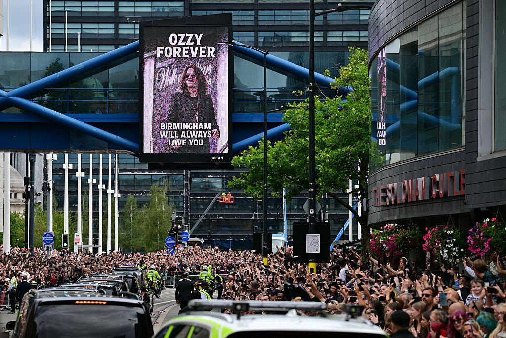 Las calles de Birmingham llenas de gente despidiendo a Ozzy, mientras que en el fondo se lee un letrero que dice "Ozzy para siempre, Birmingham siempre te amará"
