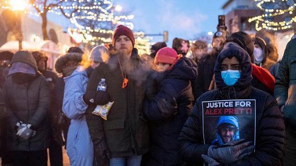 Un grupo de personas congregadas en el lugar donde murió Alex Pretti. Uno muestra un cartel que pide "justicia para Alex Pretti". 