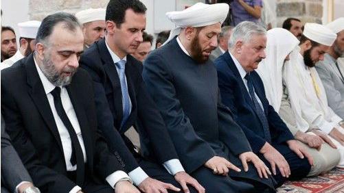 حسون يؤدي الصلاة إلى جانب الرئيس السوري المخلوع بشار الأسد وآخرين. 