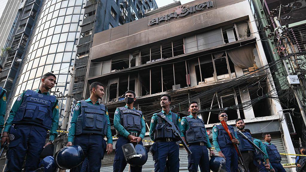 Police stand in front of the daily Prothom Alo building in Dhaka's Karwan Bazar after it was attacked, vandalised, and set on fire. 
