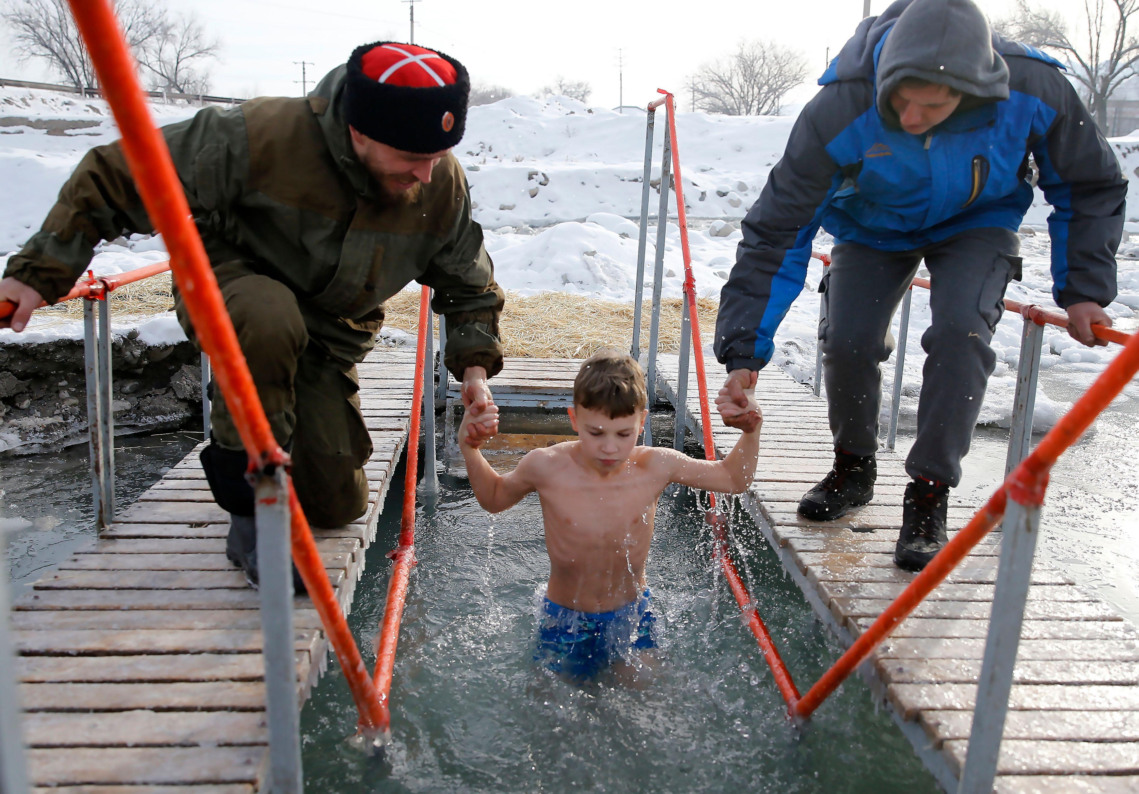 dečak se kupa u ledenoj vodi u čast bogojavljanja u kirgistanu
