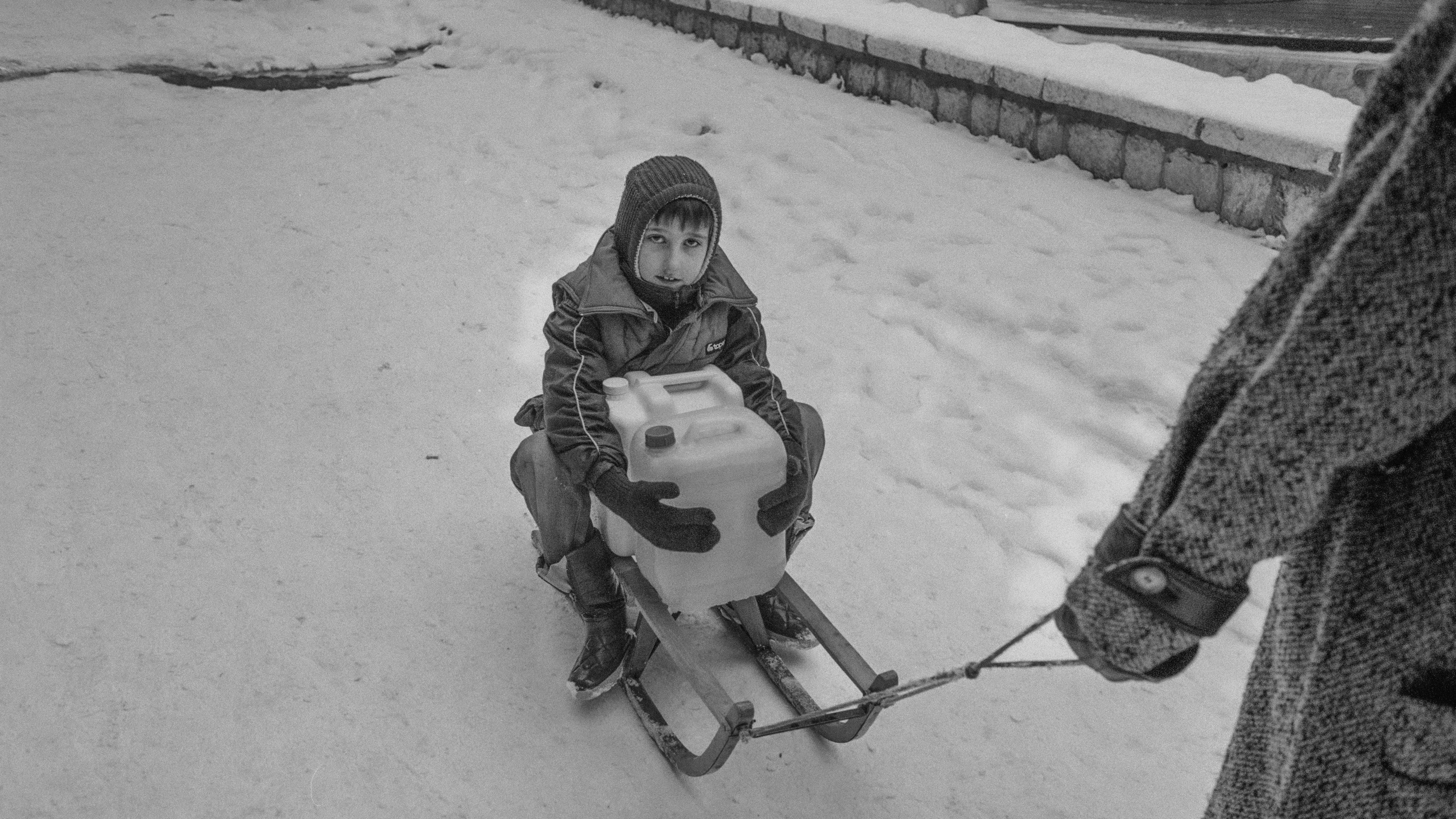 Kako odrastanje u ratu zaista utiče na jednog 11-godišnjaka 8 Dečak na sankama drži kanister sa vodom, crno-bela fotografija