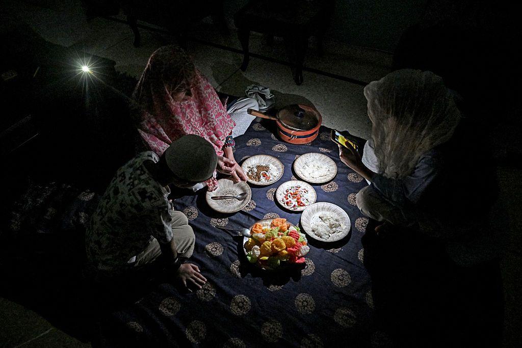 family eating dinner in the light of a mobile phone in Islamabad