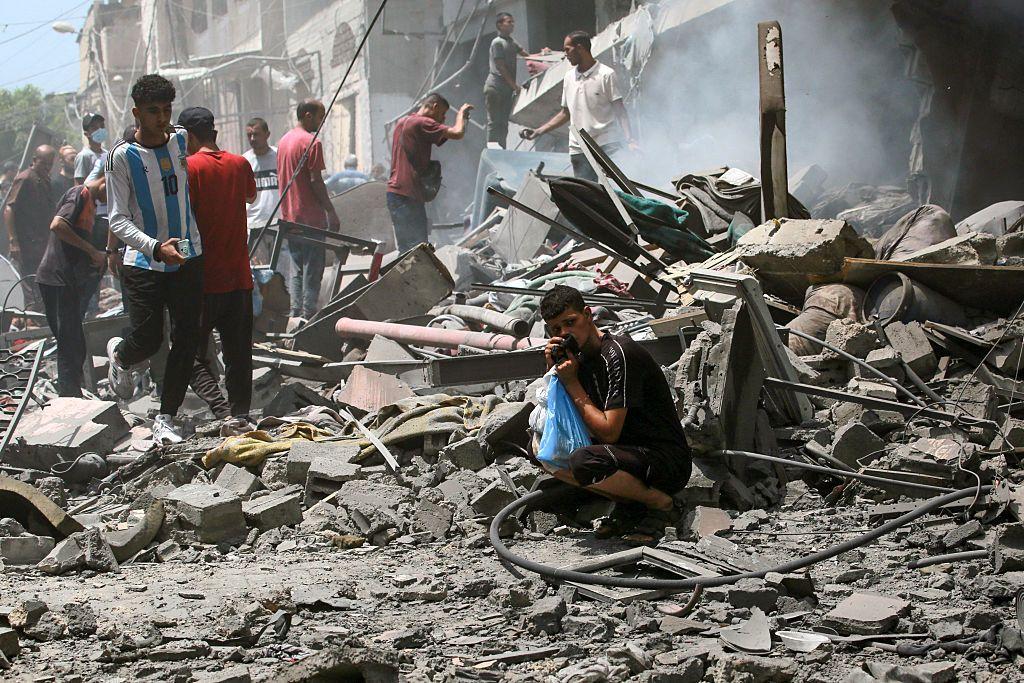 Un grupo de palestinos entre los escombros tras un ataque israelí en Ciudad de Gaza.
