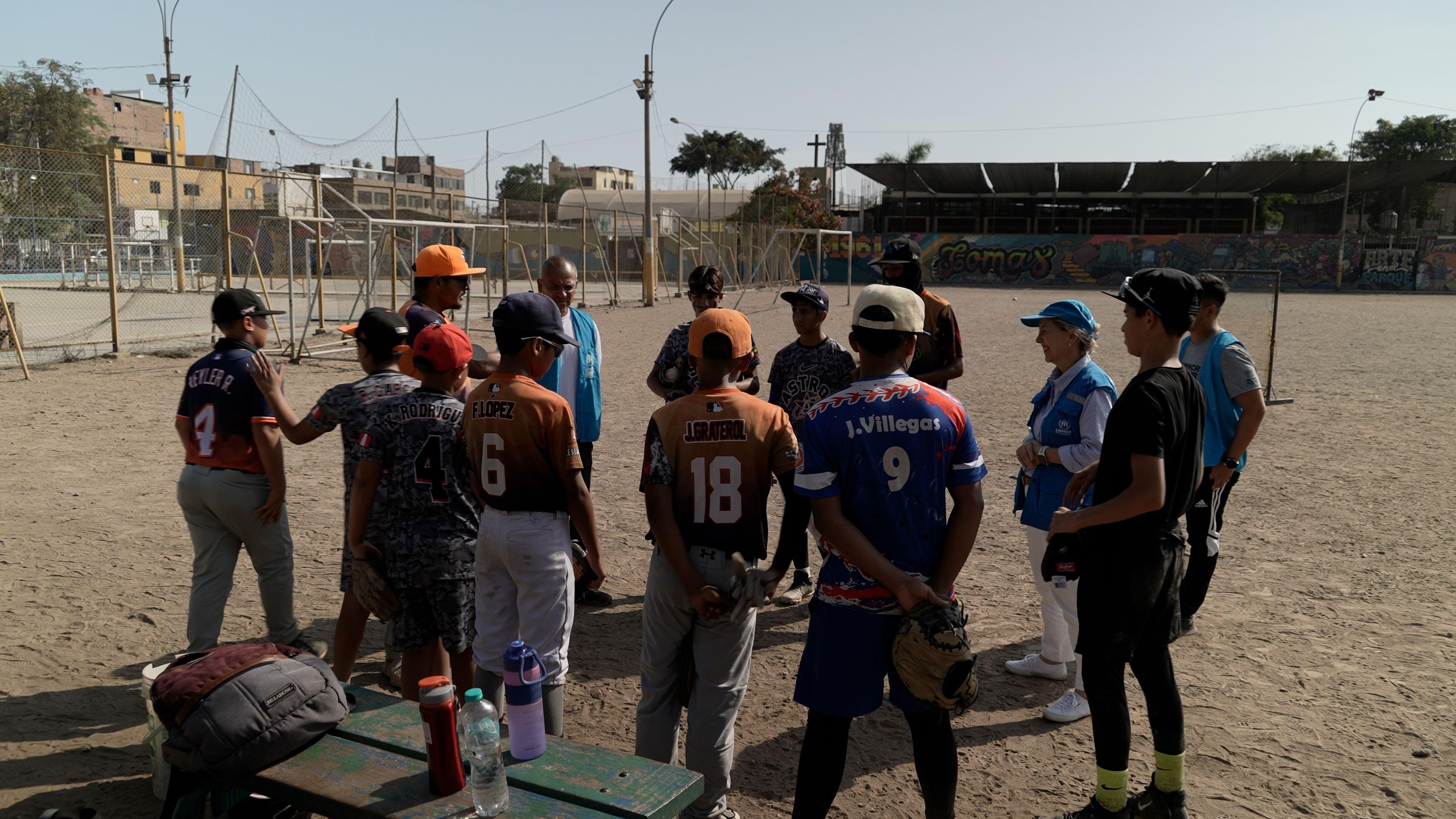 Niños escuchan a un profesor de Beisbol.
