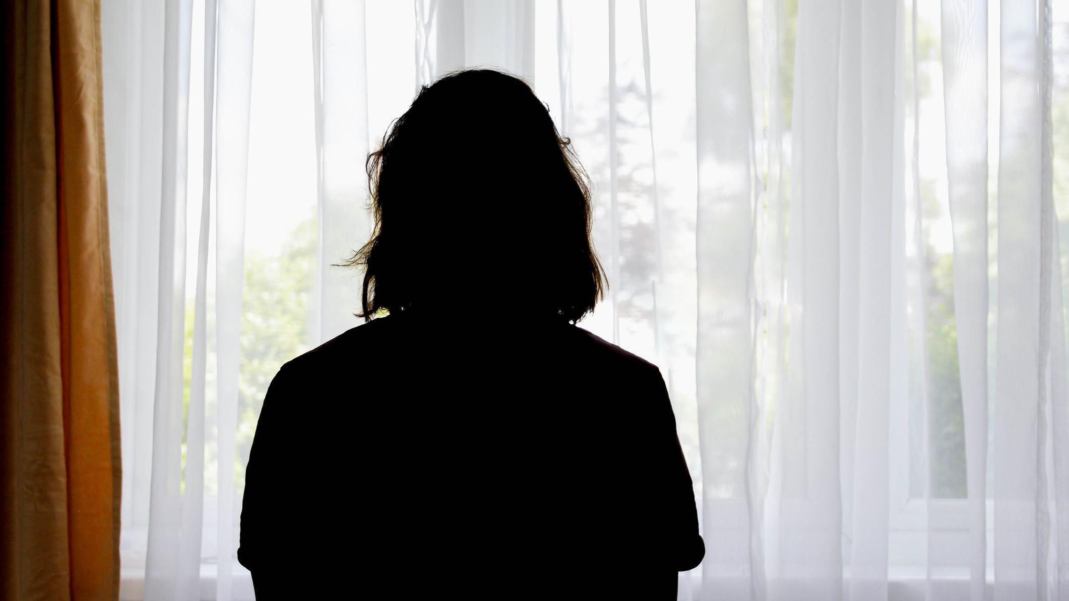 Una mujer mira hacia afuera por la ventana. 