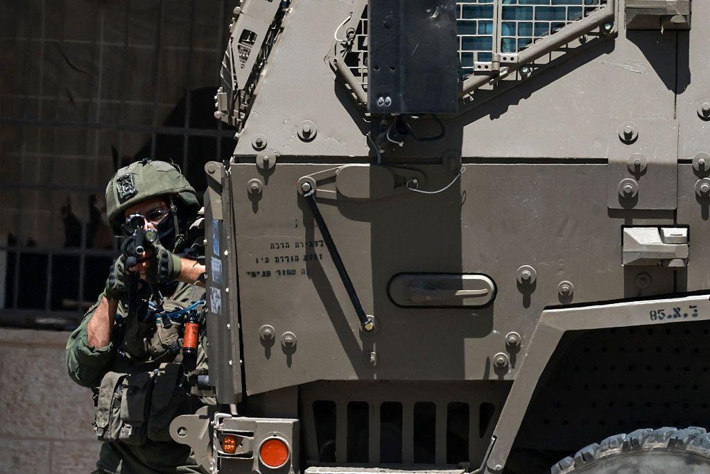 جندي إسرائيلي يصوب بندقيته خلال مداهمة محل صرافة في رام الله، بالضفة الغربية المحتلة، في 27 مايو/أيار 2025