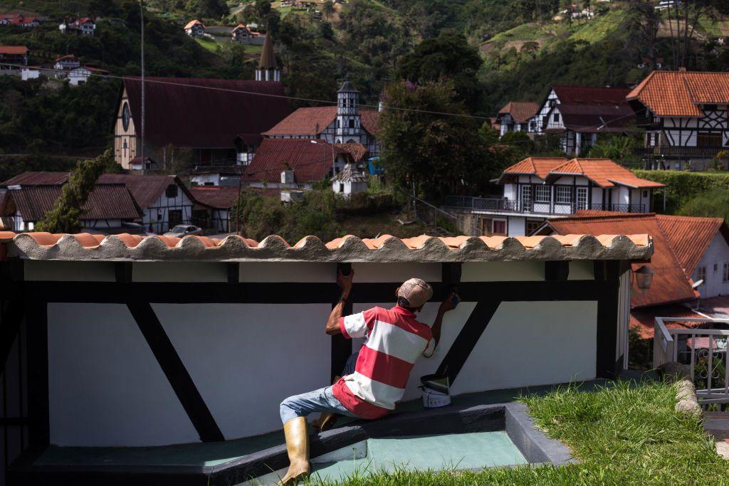 Un trabajador en un muro y de fondo se ve la Colonia Tovar con sus edificios inspirados en Alemania.