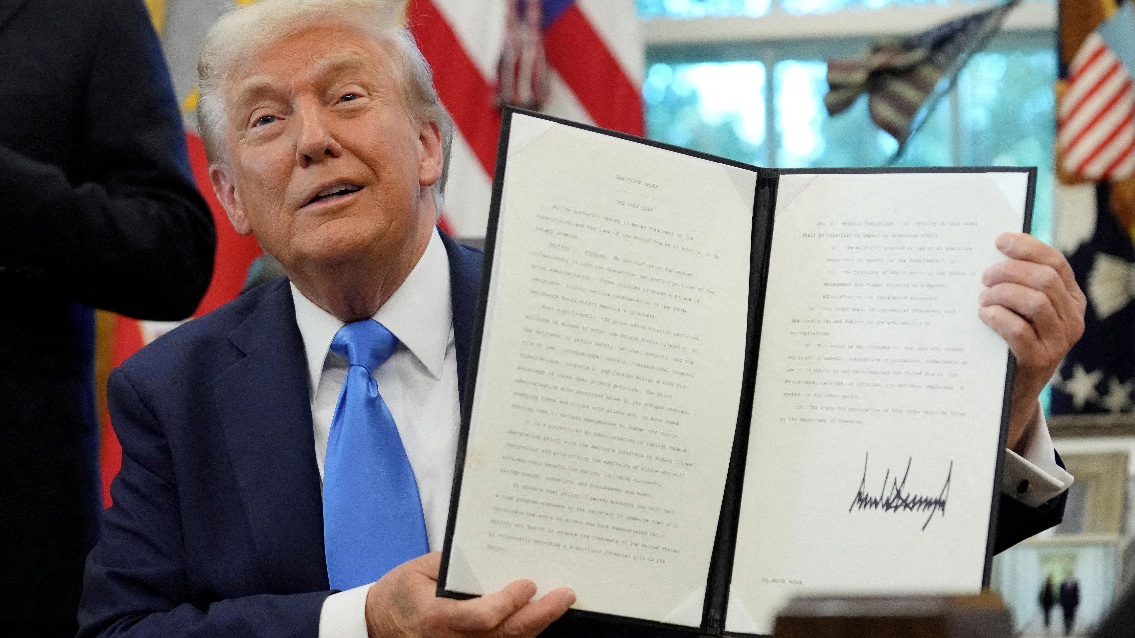 Donald Tramp se smeje dok pokazuje potpisanu uredbu o zlatnim vizama