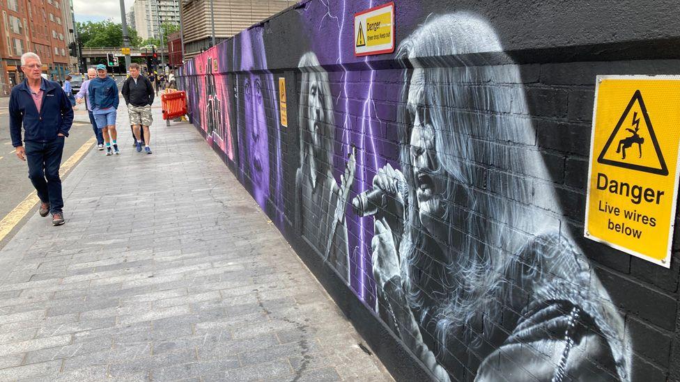 Um grande mural colorido mostrando os membros do Black Sabbath em um muro em Birmingham