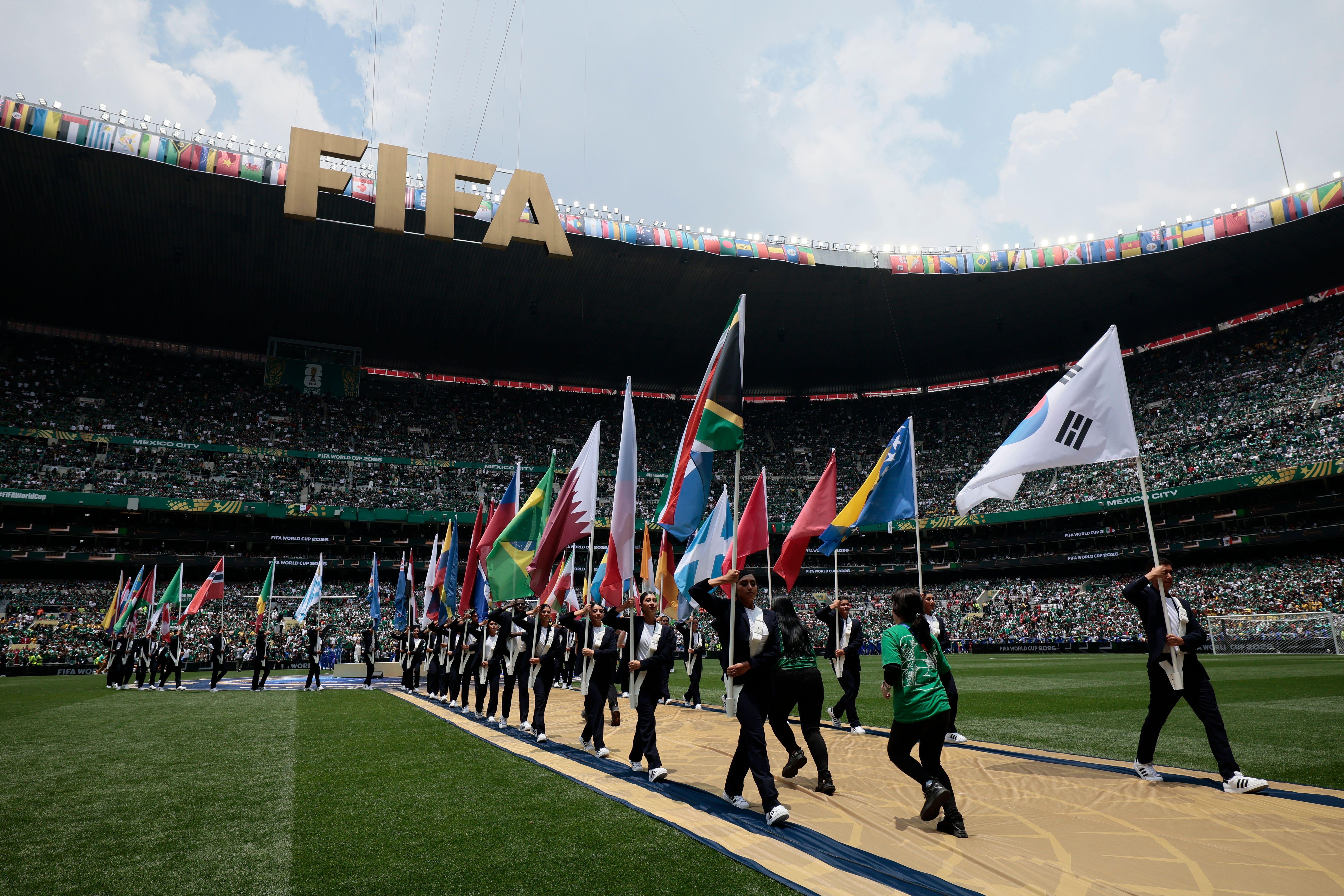 Kolona ljudi sa zastavama učesnica Mundijala na stadionu za vreme otvaranja