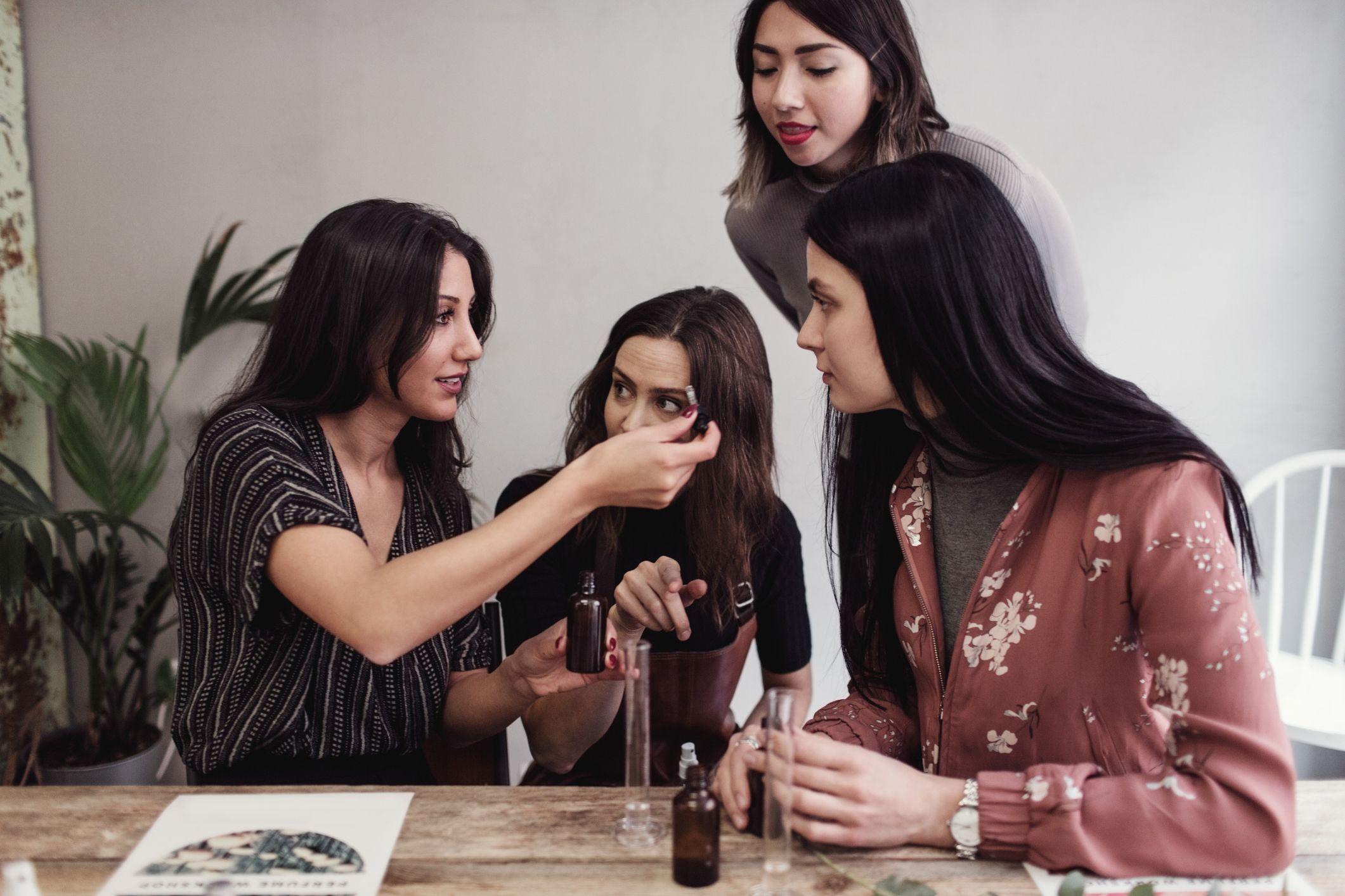 شابة بشعر أسود طويل ترتدي قميصاً بأكمام قصيرة لونه أسود ومنقط بالأبيض، تُري زميلاتها المشاركات في ورشة عمل أنبوباً يحتوي عطراً. عدد زميلاتها ثلاثة كلهن شابات ويميل لون شعرهن إلى الأسود. ترتدي واحدة منهن سترة وردية اللون بورود بيضاء، وأخرى ترتدي قميصاً يميل إلى اللون السكني والأخيرة ترتدي قميصاً قصير الأكمام بلون أسود.