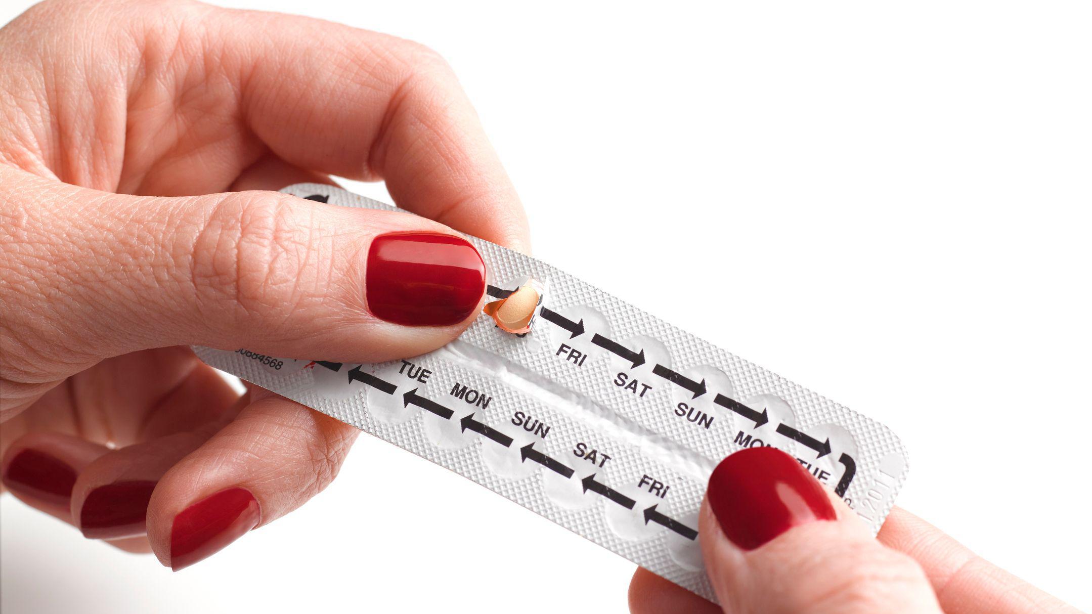 Mulher segura cartela de anticoncepcionais para uso oral