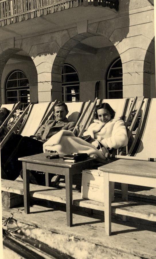 Una pareja en unas tumbonas miran sonrientes a la cámara en una imagen en blanco y negro.