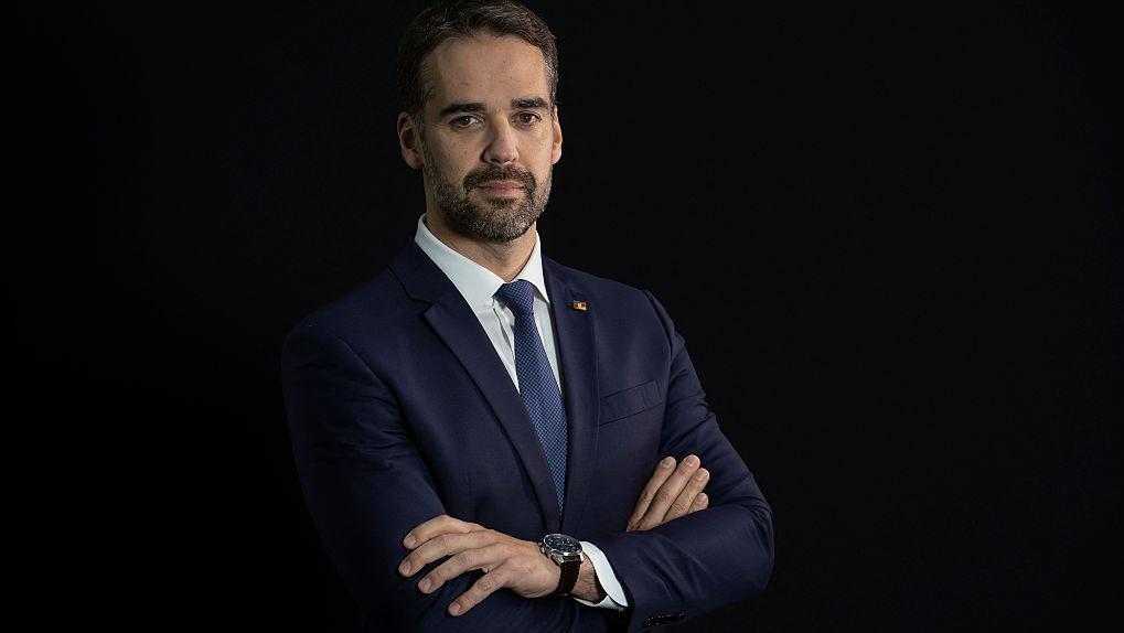 Eduardo Leite de braços cruzados e terno olhando para câmera