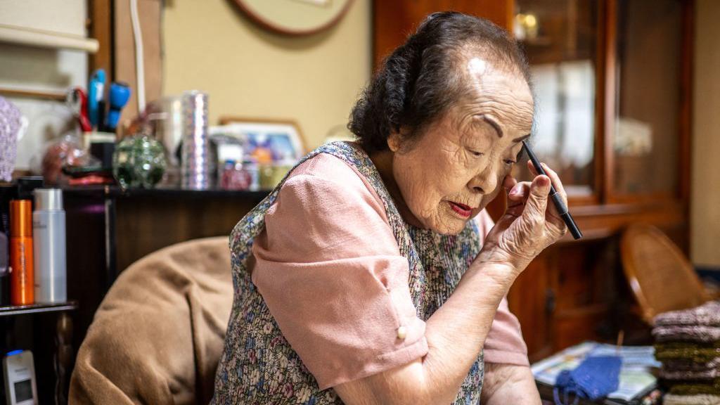 A consultora de beleza Tomoko Horino, de 100 anos, fazendo maquiagem em sua casa antes de ir para o escritório na cidade de Fukushima.