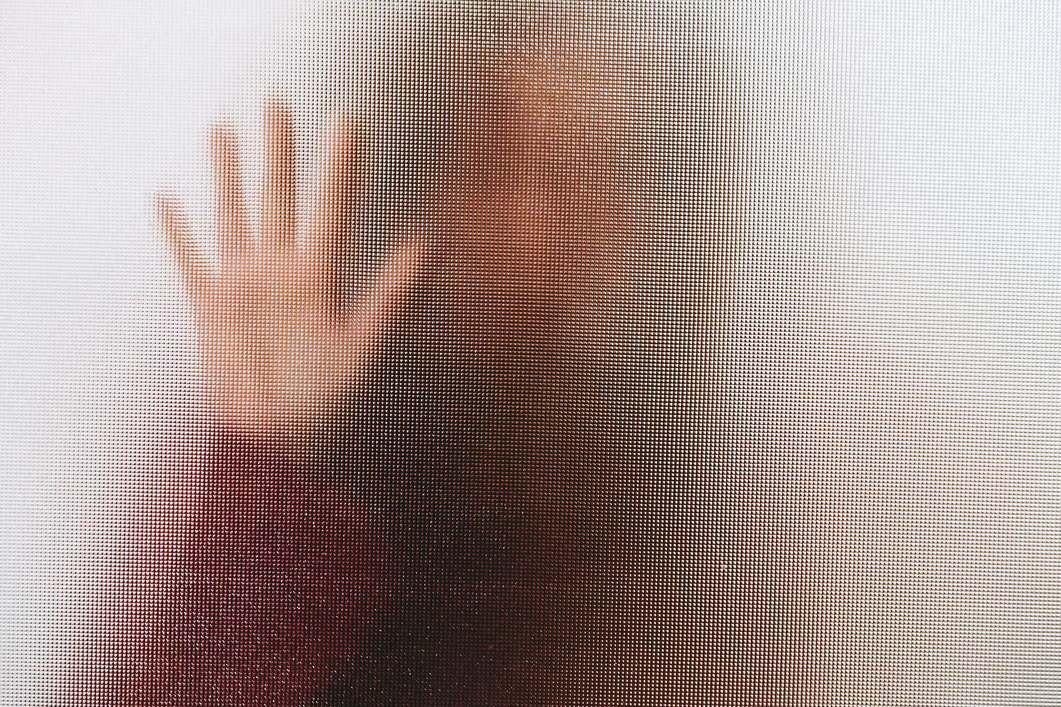 Una mujer detrás de un vidrio que no permite identificarla