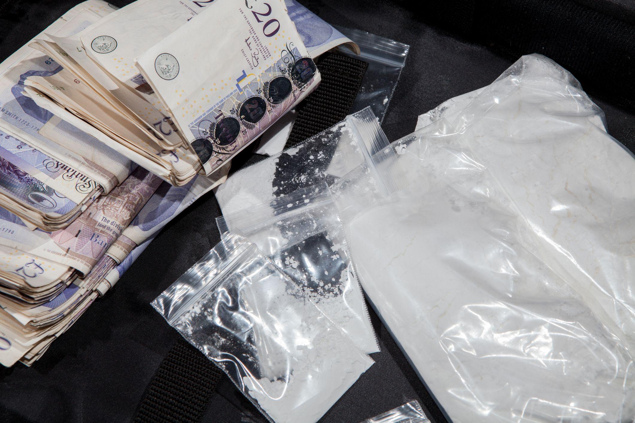 Sobres con una sustancia que simula ser cocaína junto a un fajo de billetes de 20 libras esterlinas.