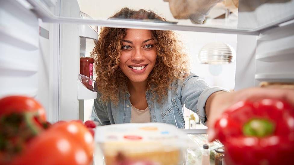 Mujer mirando el interior de su refrigerador